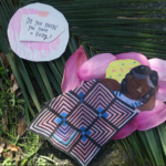 A paper illustration of a person resting on a pink flower and palm leaf, covered with a patterned blanket. A thought bubble nearby reads, Do you know you have a body?.